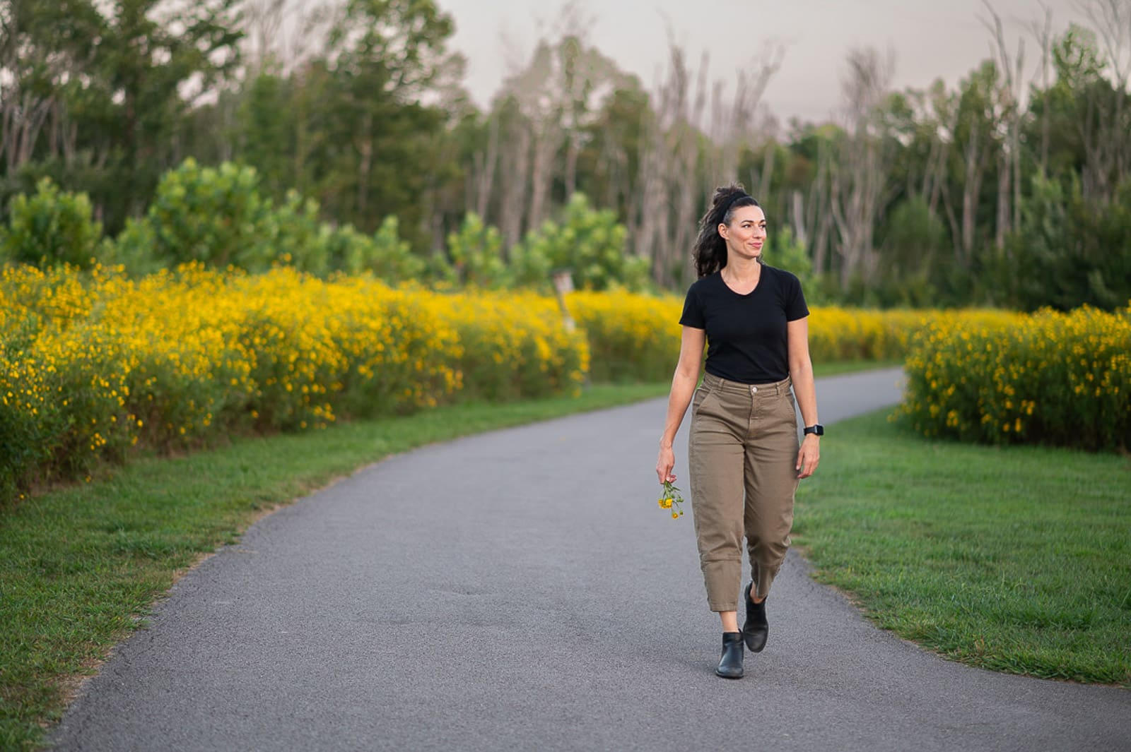 woman walking on path between lots of yellow flowers